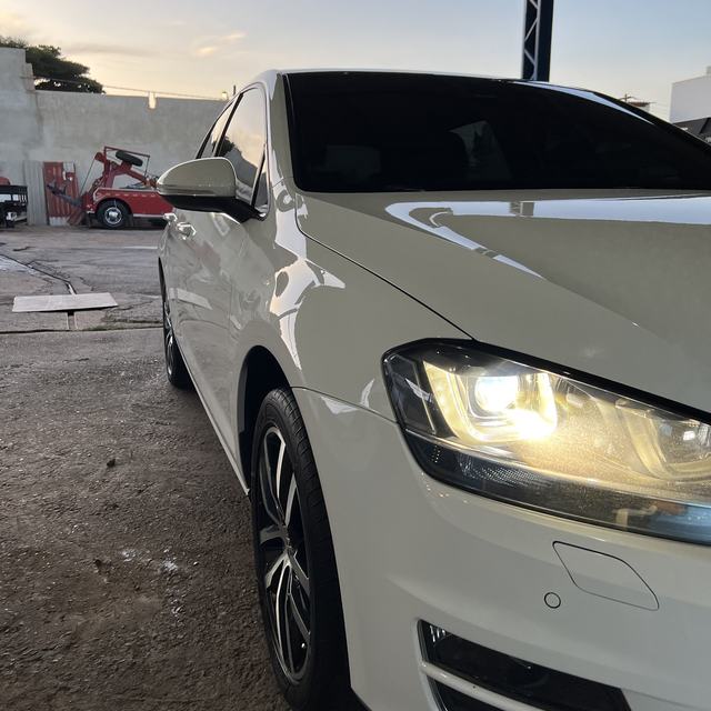 Golf branco brilhando no fim de tarde, com o farol aceso
