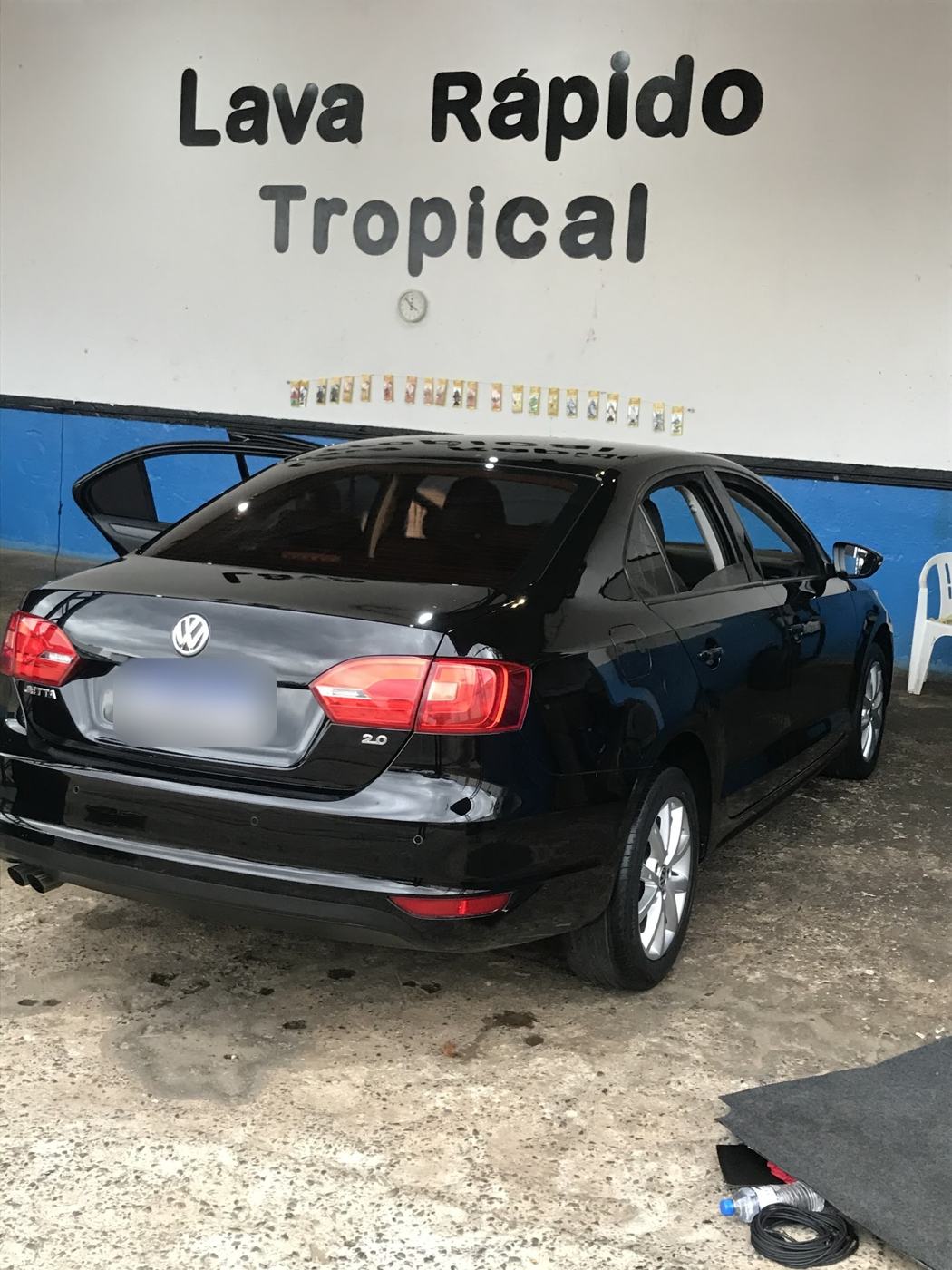Parede com o letreiro Lava Rápido Tropical e um Jetta preto recém-lavado